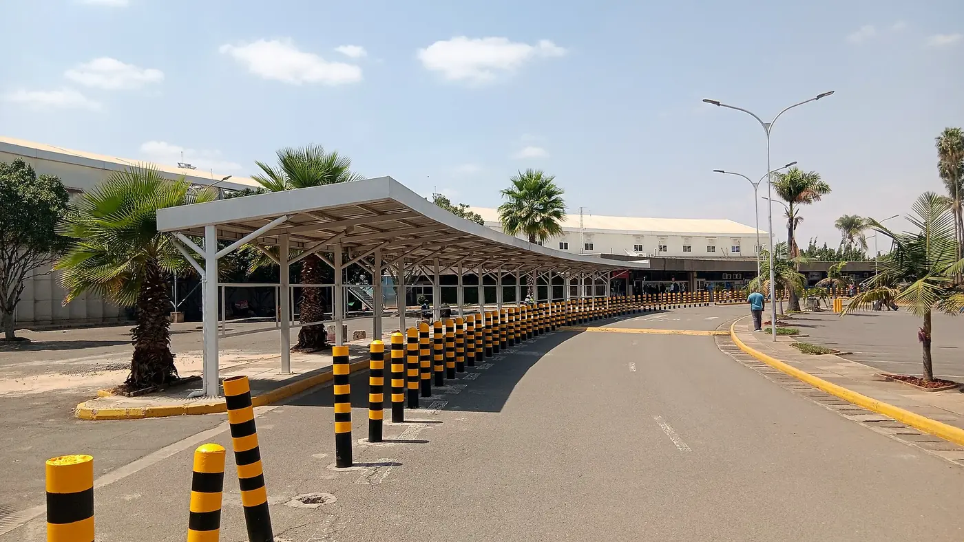 Covered terminal road with palms at Jomo Kenyatta International Airport, where layover pickups meet arriving passengers
